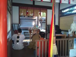 源九郎稲荷神社で執り行われた鳴釜神事の様子。参列者と修験僧が拝殿内で神事を見守る風景